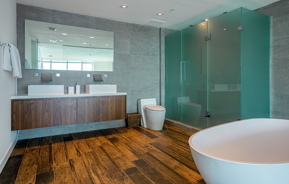 Contemporary bathroom in Miami with dark wood cabinets, a freestanding tub, a corner shower and a one-piece toilet.