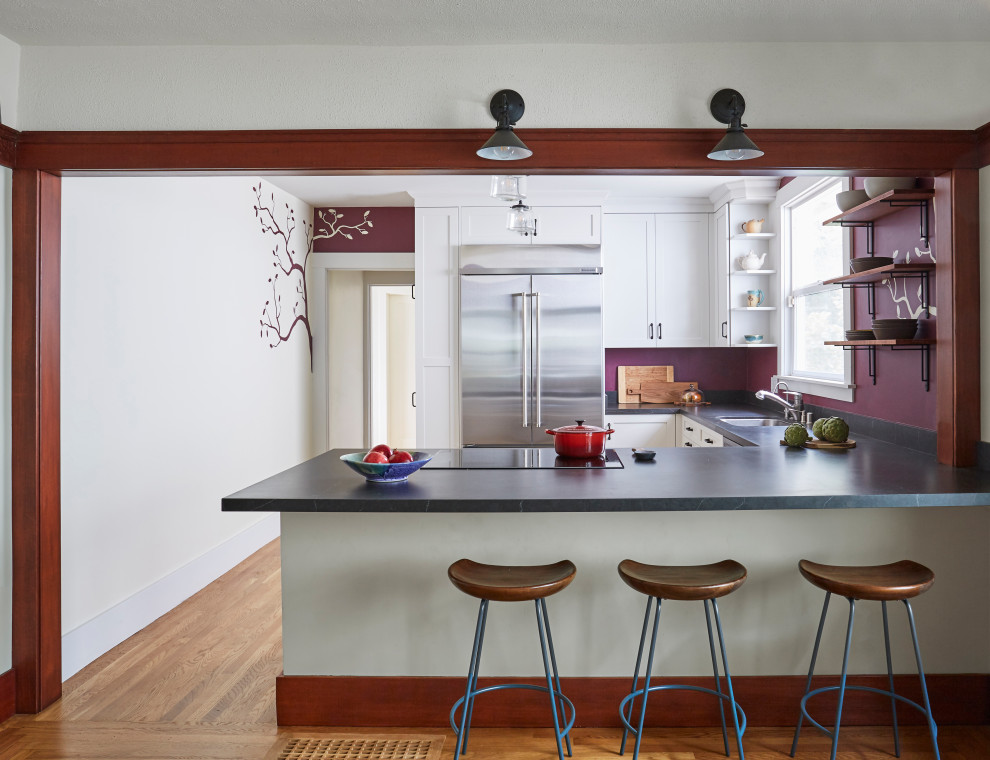 Photo of a mid-sized asian u-shaped separate kitchen in San Francisco with an undermount sink, shaker cabinets, white cabinets, stainless steel appliances, medium hardwood floors, a peninsula, brown floor, grey benchtop and soapstone benchtops.