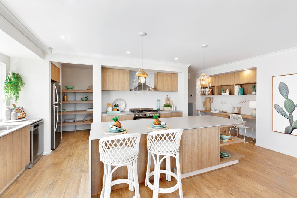 Beach style l-shaped kitchen in Melbourne with an undermount sink, flat-panel cabinets, medium wood cabinets, stainless steel appliances, medium hardwood floors, with island, brown floor and white benchtop.