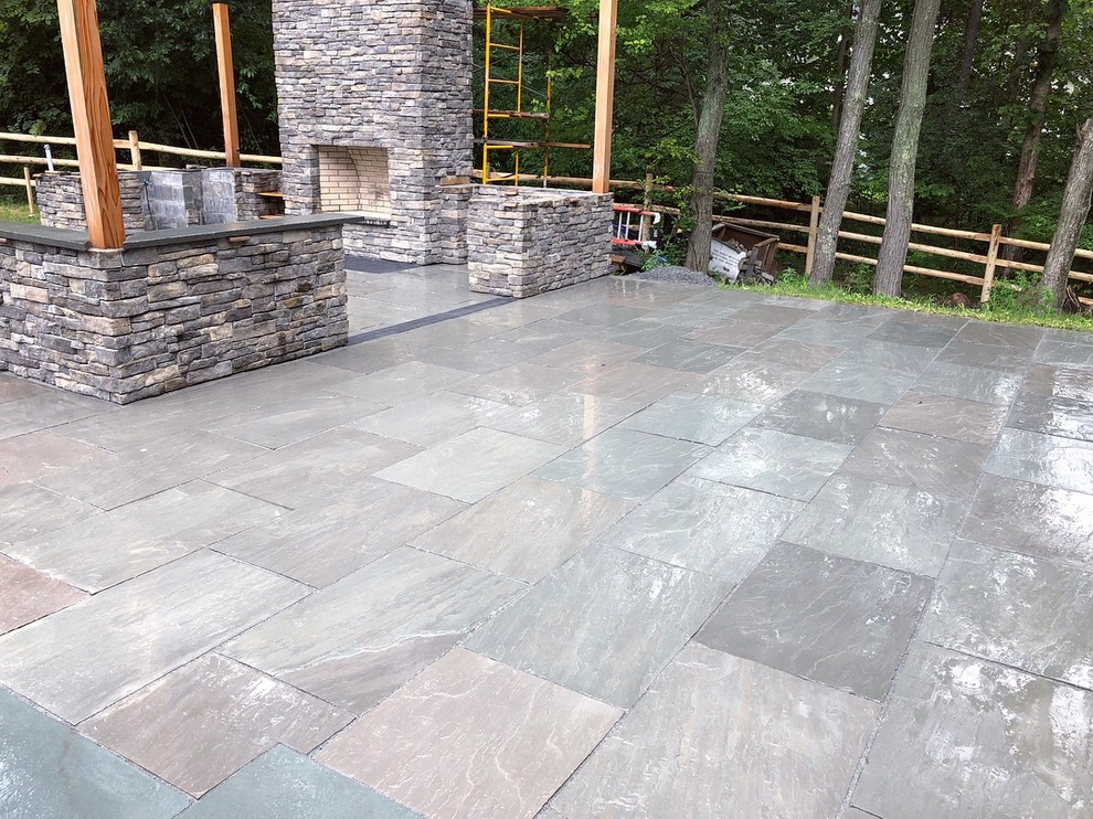 Contemporary backyard partial sun garden in New York with with fireplace and natural stone pavers for summer.