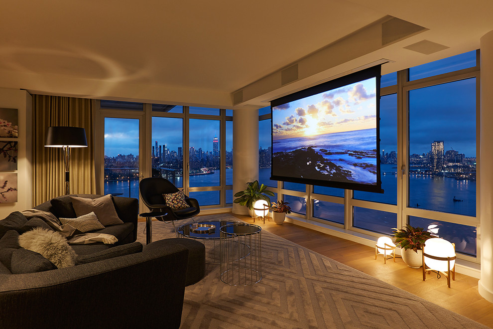 Inspiration for a large contemporary open concept home theatre in New York with beige walls, light hardwood floors, a projector screen and brown floor.