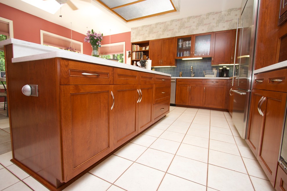 Transitional l-shaped ceramic tile open concept kitchen photo in Baltimore with an undermount sink, recessed-panel cabinets, medium tone wood cabinets, solid surface countertops, blue backsplash, ceramic backsplash, stainless steel appliances and an island