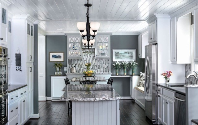 Example of a large transitional dark wood floor and brown floor eat-in kitchen design with an undermount sink, recessed-panel cabinets, white cabinets, granite countertops, gray backsplash, glass tile backsplash, stainless steel appliances and an island