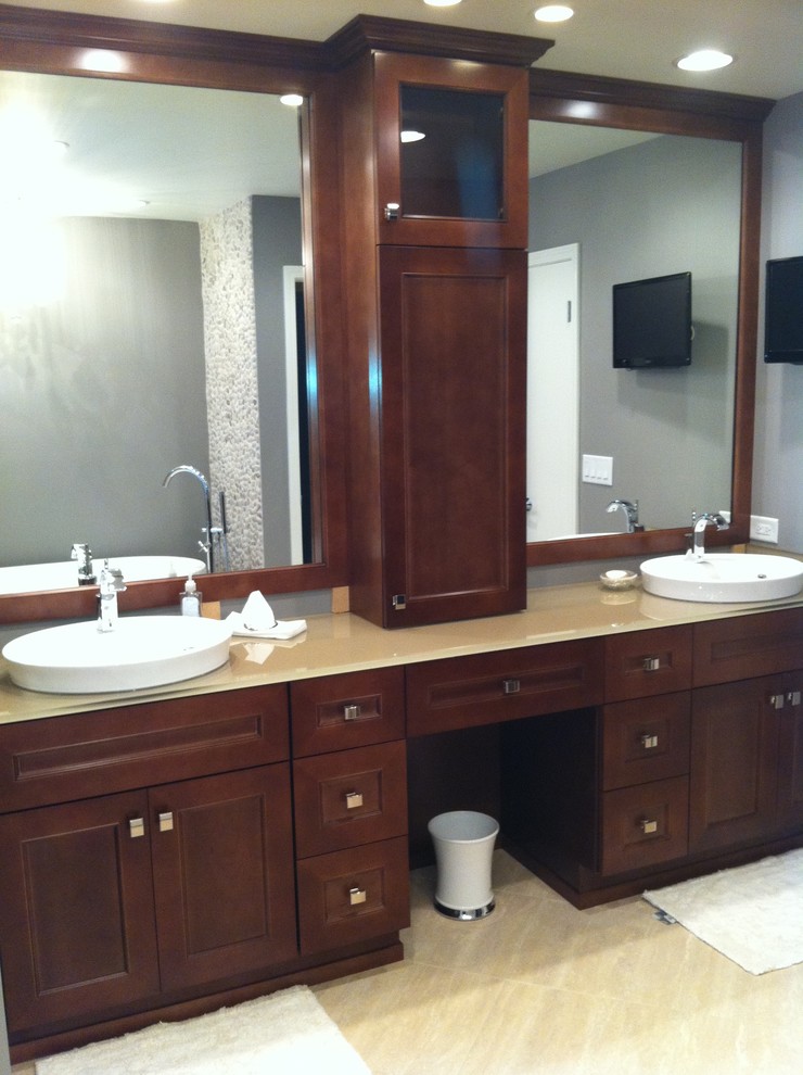 Inspiration for a mid-sized contemporary master bathroom in Chicago with a vessel sink, shaker cabinets, medium wood cabinets, glass benchtops, a freestanding tub, a corner shower, a one-piece toilet, beige tile, porcelain tile, grey walls and porcelain floors.