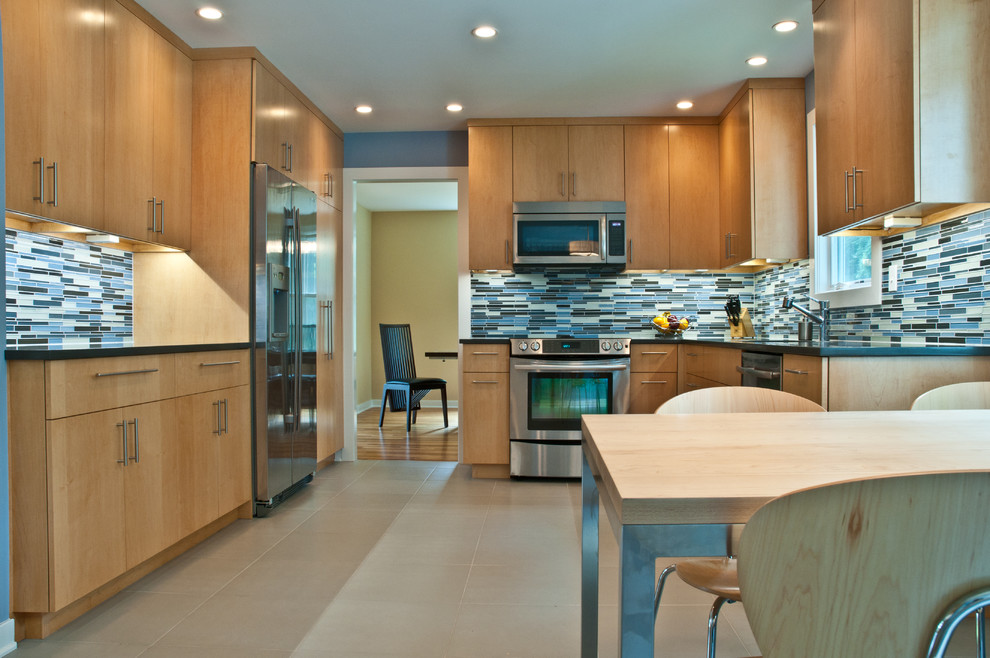 Photo of a small contemporary u-shaped eat-in kitchen in Philadelphia with an undermount sink, flat-panel cabinets, light wood cabinets, solid surface benchtops, blue splashback, glass tile splashback, stainless steel appliances, ceramic floors and no island.