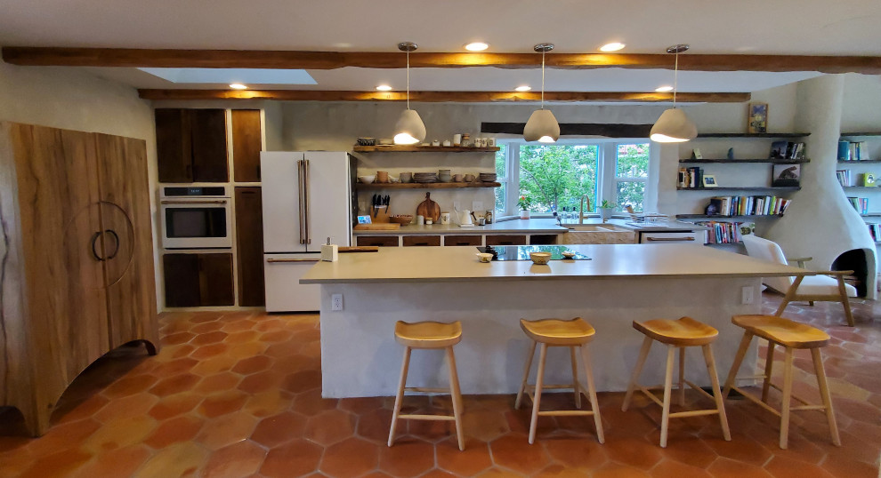 Medelhavsstil inredning av ett stort grå linjärt grått kök med öppen planlösning, med en rustik diskho, släta luckor, skåp i mörkt trä, bänkskiva i kvarts, beige stänkskydd, stänkskydd i kalk, vita vitvaror, klinkergolv i terrakotta, en köksö och orange golv