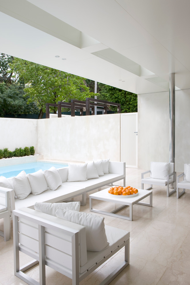 Modern backyard patio in Melbourne with natural stone pavers and a roof extension.