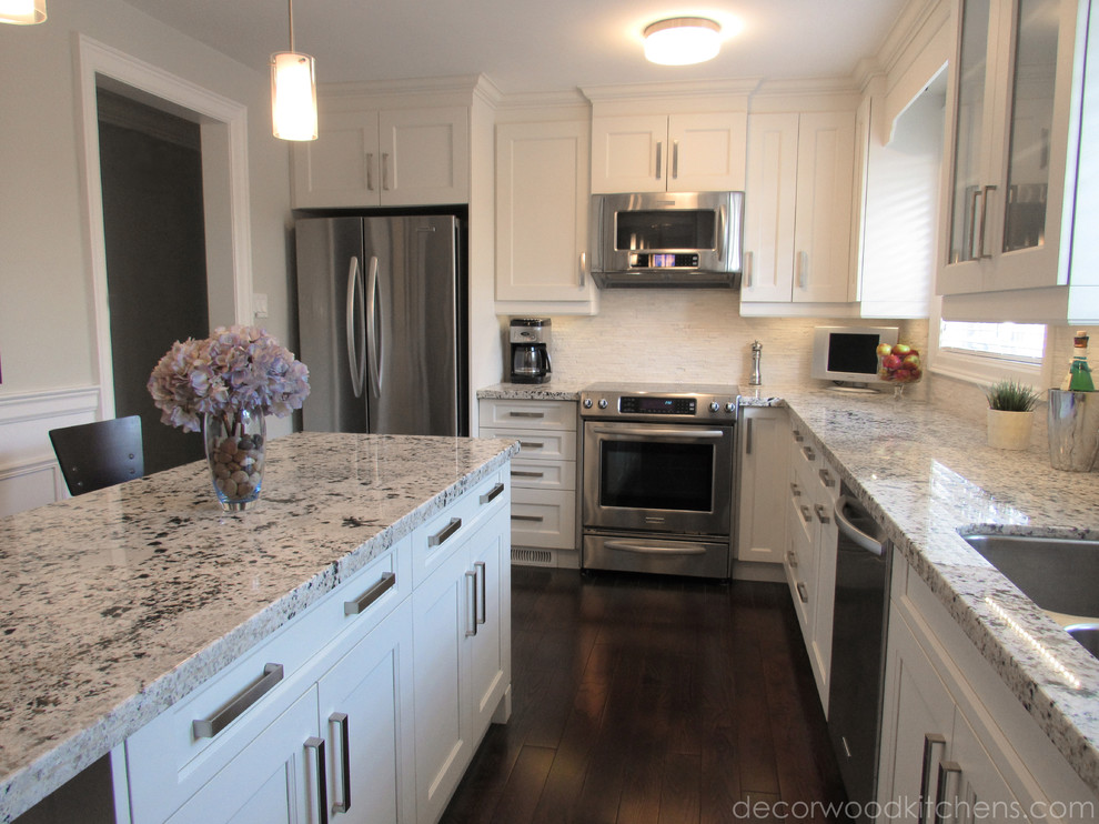 Example of a mid-sized transitional l-shaped dark wood floor enclosed kitchen design in Toronto with an undermount sink, flat-panel cabinets, white cabinets, granite countertops, white backsplash, stone tile backsplash, stainless steel appliances and an island