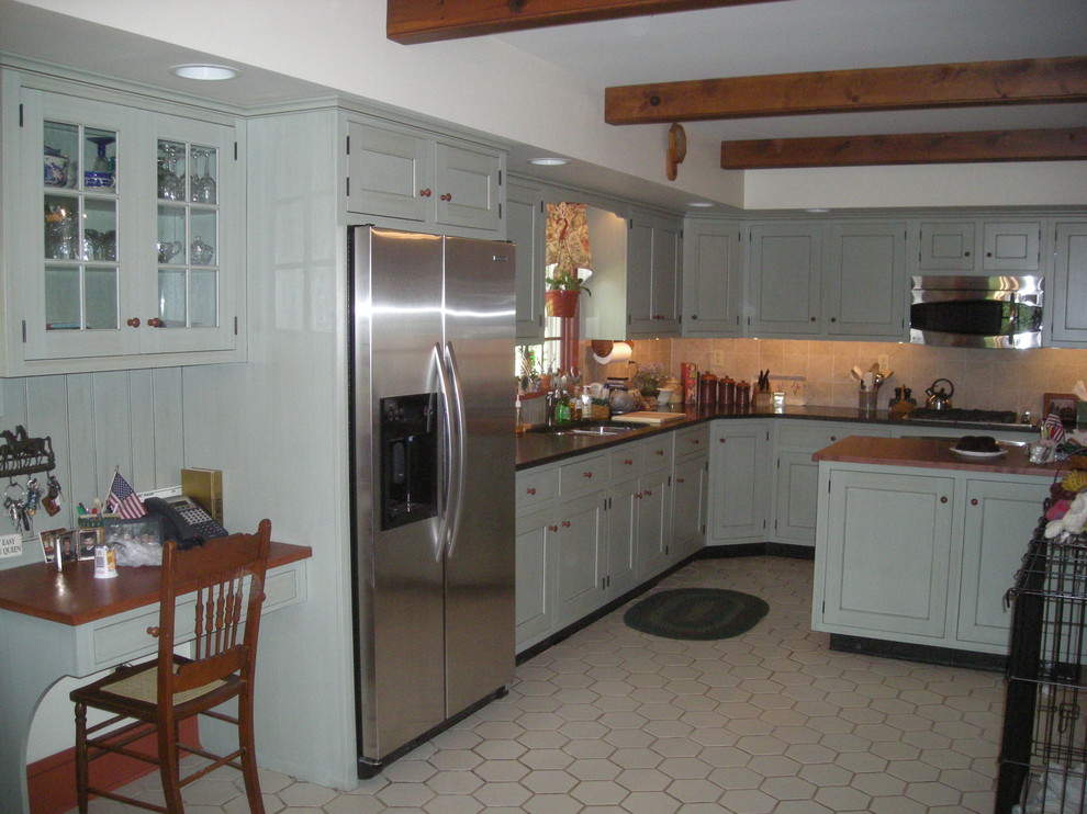 Inspiration for a large country l-shaped eat-in kitchen in Philadelphia with a double-bowl sink, recessed-panel cabinets, green cabinets, granite benchtops, beige splashback, stone tile splashback, stainless steel appliances, porcelain floors and with island.