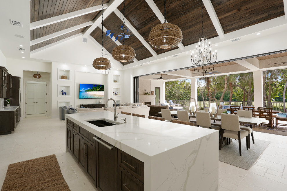 This is an example of a large modern kitchen in Tampa with a drop-in sink, dark wood cabinets, marble benchtops, white splashback, stainless steel appliances, travertine floors, with island, white floor, white benchtop and wood.