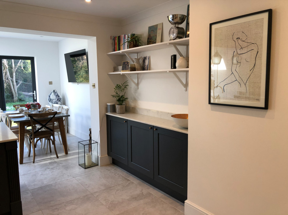 Traditional l-shaped open plan kitchen in Manchester with a belfast sink, shaker cabinets, blue cabinets, quartz worktops, an island and white worktops.