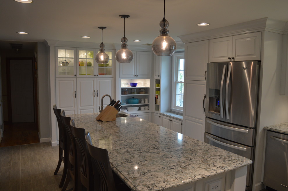 Inspiration for a large transitional u-shaped ceramic tile and gray floor enclosed kitchen remodel with a farmhouse sink, raised-panel cabinets, white cabinets, quartz countertops, gray backsplash, glass tile backsplash, stainless steel appliances and an island