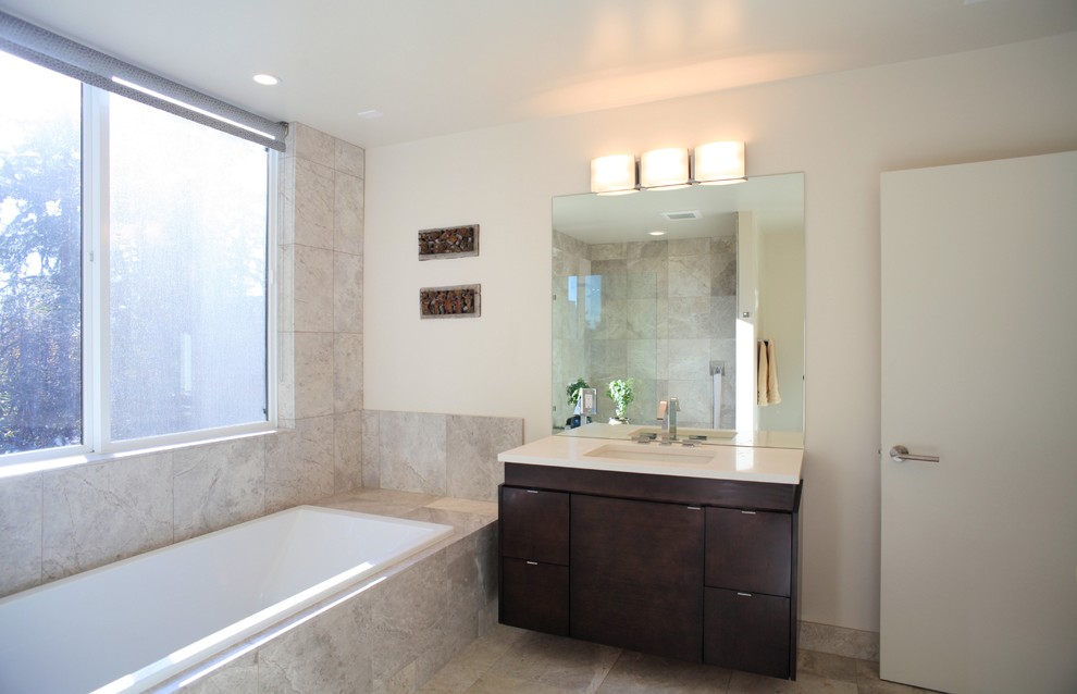 Inspiration for a large modern master bathroom in Seattle with an undermount sink, flat-panel cabinets, dark wood cabinets, engineered quartz benchtops, a drop-in tub, an open shower, a two-piece toilet, gray tile, stone tile, white walls, limestone floors and brown floor.