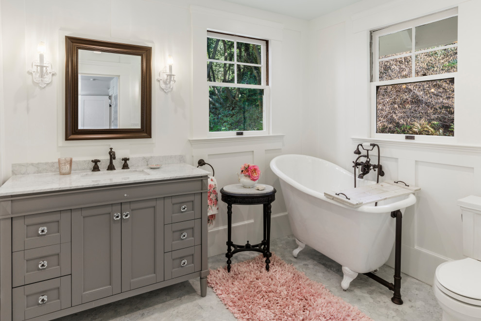 Photo of a transitional bathroom in San Francisco with recessed-panel cabinets, grey cabinets, a claw-foot tub, white walls, an undermount sink, grey floor and white benchtops.