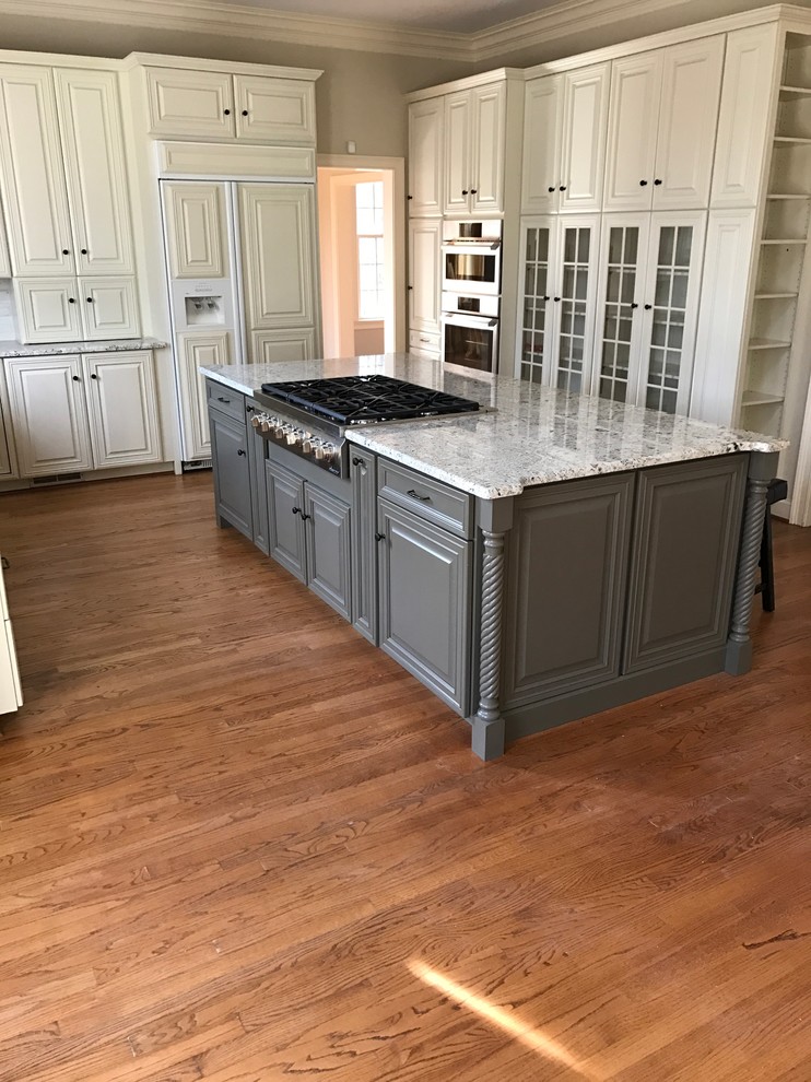 Design ideas for a large traditional u-shaped eat-in kitchen in Other with an undermount sink, raised-panel cabinets, grey cabinets, granite benchtops, stainless steel appliances, medium hardwood floors, with island, brown floor and grey benchtop.
