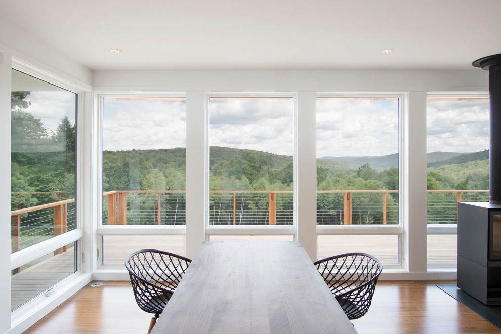 Immagine di una sala da pranzo aperta verso il soggiorno minimalista di medie dimensioni con pareti bianche, pavimento in bambù, stufa a legna e pavimento marrone