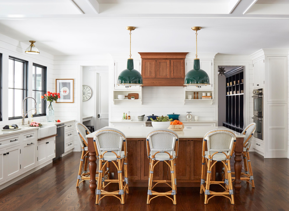 Design ideas for a large country u-shaped open plan kitchen in Chicago with a farmhouse sink, recessed-panel cabinets, white cabinets, quartz benchtops, white splashback, shiplap splashback, stainless steel appliances, medium hardwood floors, with island, brown floor and white benchtop.