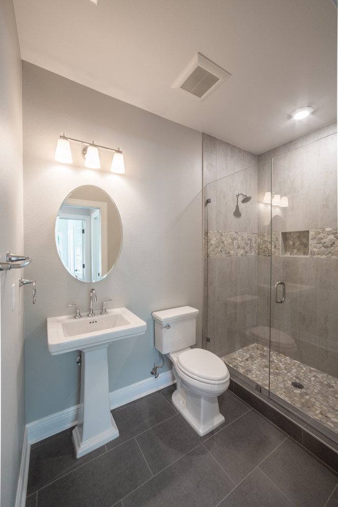 Mid-sized elegant 3/4 multicolored tile and porcelain tile porcelain tile, gray floor and single-sink alcove shower photo with a one-piece toilet, gray walls, a pedestal sink, a hinged shower door and a niche