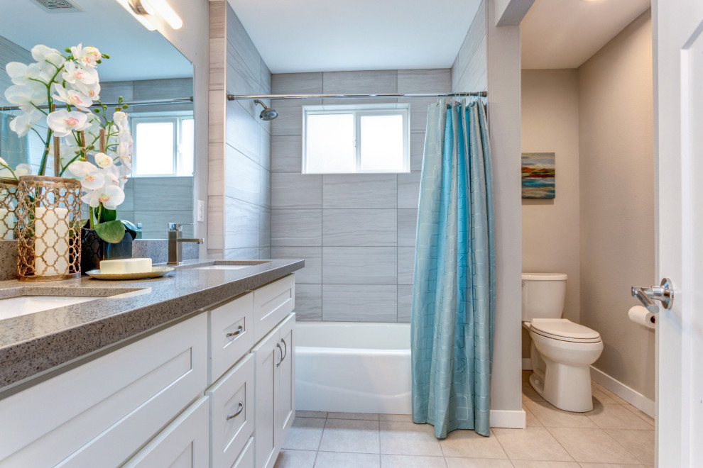 Inspiration for a mid-sized contemporary master bathroom in San Diego with a shower/bathtub combo, a one-piece toilet, gray tile, subway tile, grey walls, ceramic floors, an undermount sink, quartzite benchtops, beige floor, a shower curtain, grey benchtops, an enclosed toilet and a double vanity.