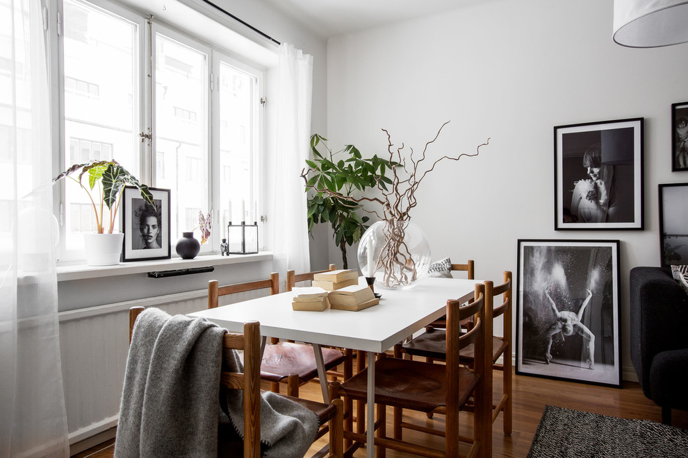 Photo of a mid-sized scandinavian dining room in Stockholm with white walls, medium hardwood floors and no fireplace.