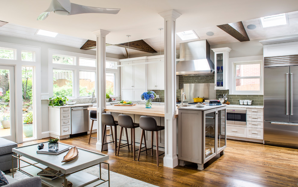 Inspiration for a transitional l-shaped open plan kitchen in Atlanta with wood benchtops, medium hardwood floors, with island, shaker cabinets, white cabinets, green splashback, subway tile splashback and stainless steel appliances.