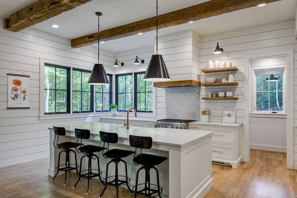 Photo of a country kitchen in Other with a farmhouse sink, beaded inset cabinets, white cabinets, medium hardwood floors, with island and brown floor.