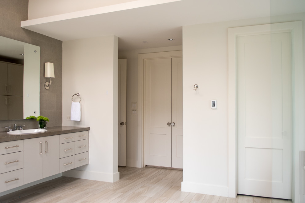 Mid-sized transitional master gray tile and cement tile light wood floor and beige floor drop-in bathtub photo in Dallas with flat-panel cabinets, gray cabinets, gray walls, a drop-in sink, concrete countertops and a hinged shower door