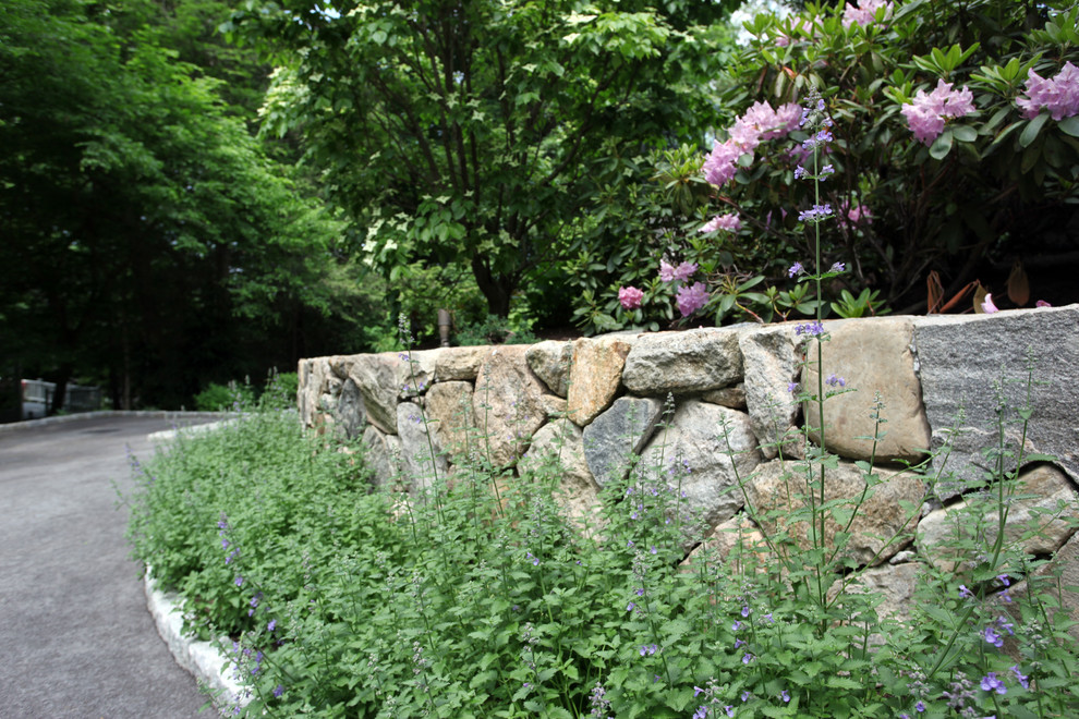Photo of a large traditional garden in New York with a retaining wall and natural stone pavers.