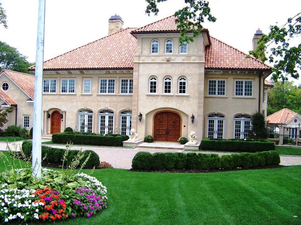 This is an example of a mediterranean three-storey adobe beige house exterior in New York with a gambrel roof and a tile roof.