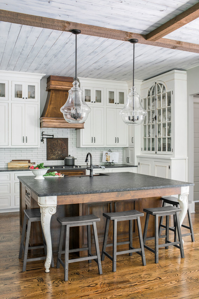 Inspiration for a mid-sized country l-shaped kitchen in Atlanta with white cabinets, white splashback, medium hardwood floors, with island, brown floor, grey benchtop and beaded inset cabinets.