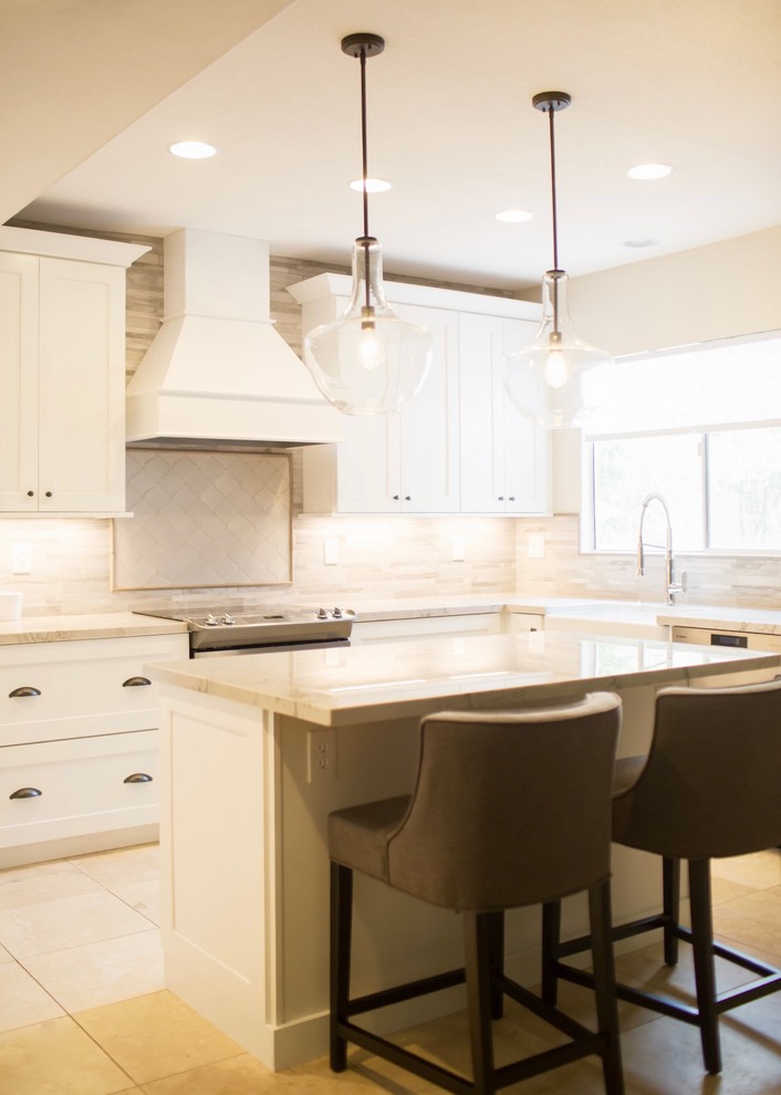 Mid-sized transitional l-shaped kitchen in Phoenix with a farmhouse sink, shaker cabinets, white cabinets, quartzite benchtops, grey splashback, porcelain splashback, stainless steel appliances, porcelain floors and with island.