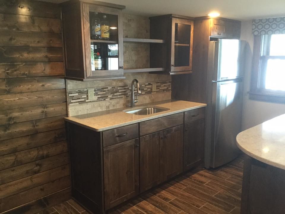Inspiration for a small arts and crafts galley wet bar in Minneapolis with an undermount sink, flat-panel cabinets, dark wood cabinets, quartz benchtops, beige splashback, travertine splashback, porcelain floors, brown floor and beige benchtop.