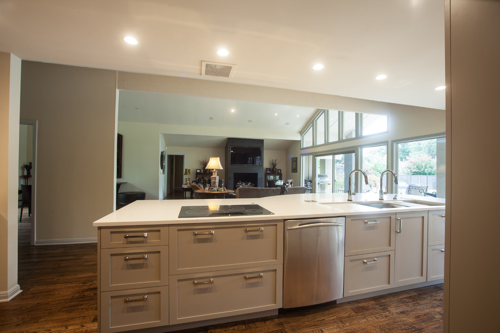 Large trendy medium tone wood floor and brown floor open concept kitchen photo with an undermount sink, shaker cabinets, beige cabinets, quartzite countertops, white backsplash, mosaic tile backsplash, stainless steel appliances and an island