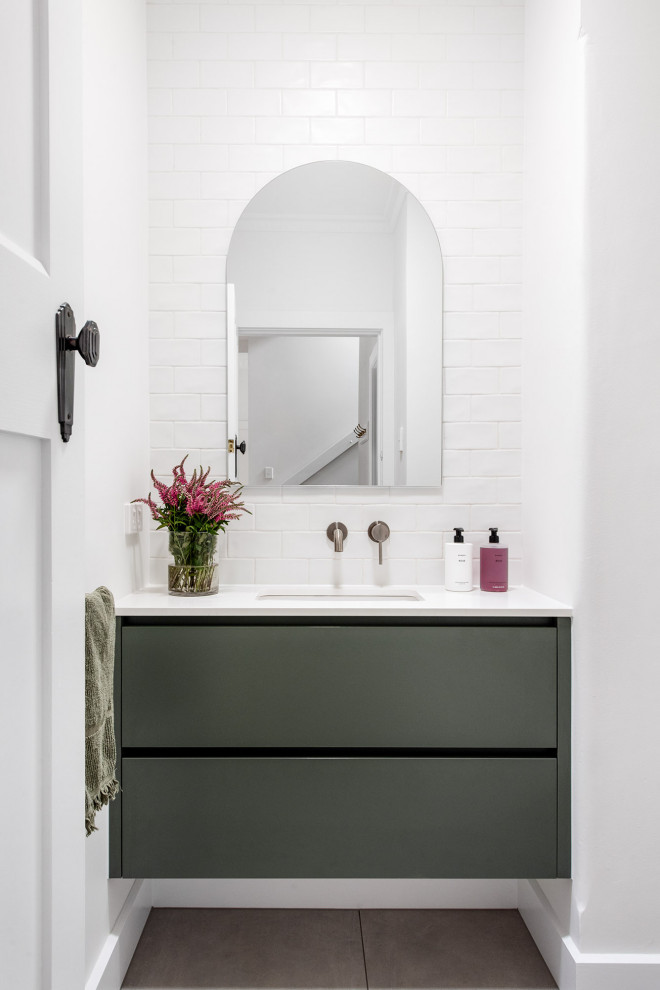 Inspiration for a small contemporary powder room in Melbourne with flat-panel cabinets, green cabinets, a one-piece toilet, white tile, subway tile, white walls, ceramic floors, an undermount sink, limestone benchtops, grey floor, white benchtops and a floating vanity.