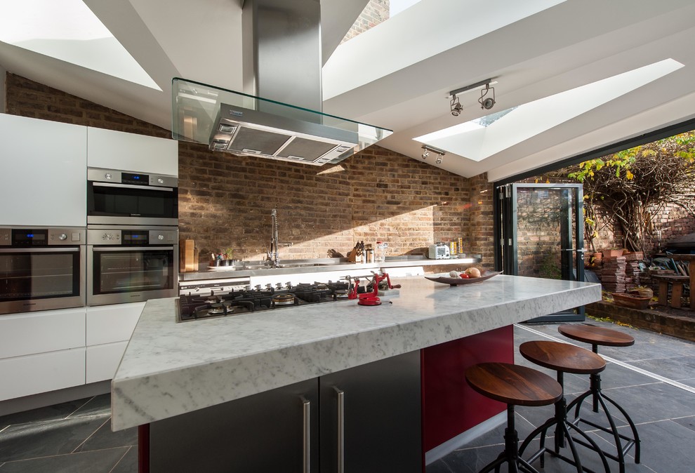 This is an example of a mid-sized contemporary single-wall eat-in kitchen in London with an integrated sink, flat-panel cabinets, white cabinets, marble benchtops, stainless steel appliances, ceramic floors and with island.