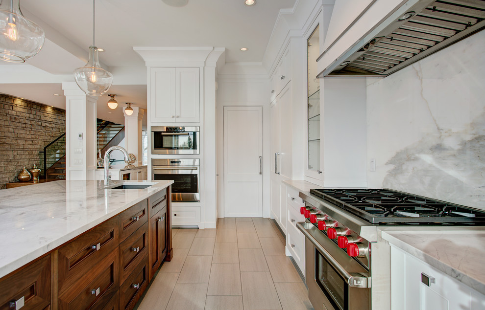 Transitional porcelain tile eat-in kitchen photo in Calgary with shaker cabinets, white cabinets, marble countertops, white backsplash, stone slab backsplash, stainless steel appliances, an island and an undermount sink