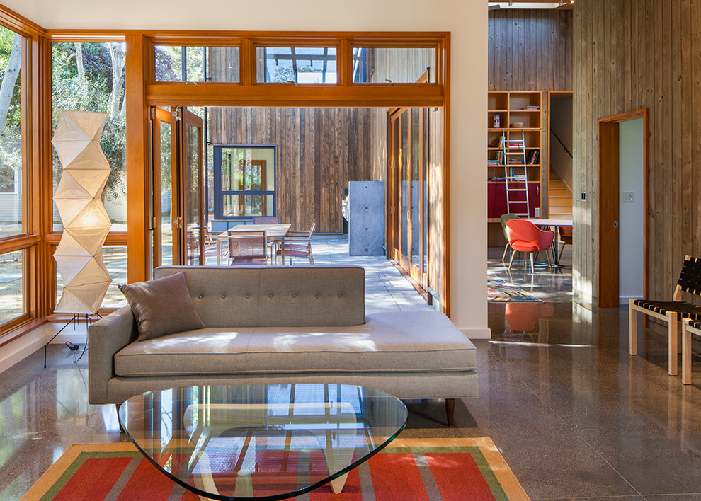 This is an example of a large contemporary open concept living room in San Francisco with multi-coloured walls, concrete floors, no fireplace, no tv and a library.