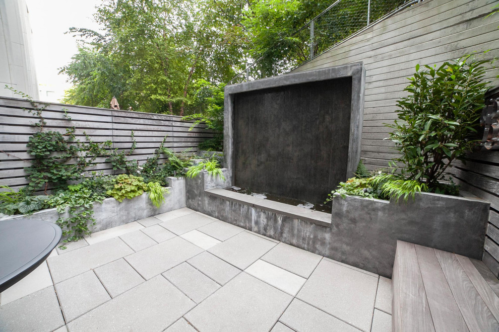 Imagen de terraza planta baja moderna de tamaño medio sin cubierta en patio trasero con fuente y barandilla de madera