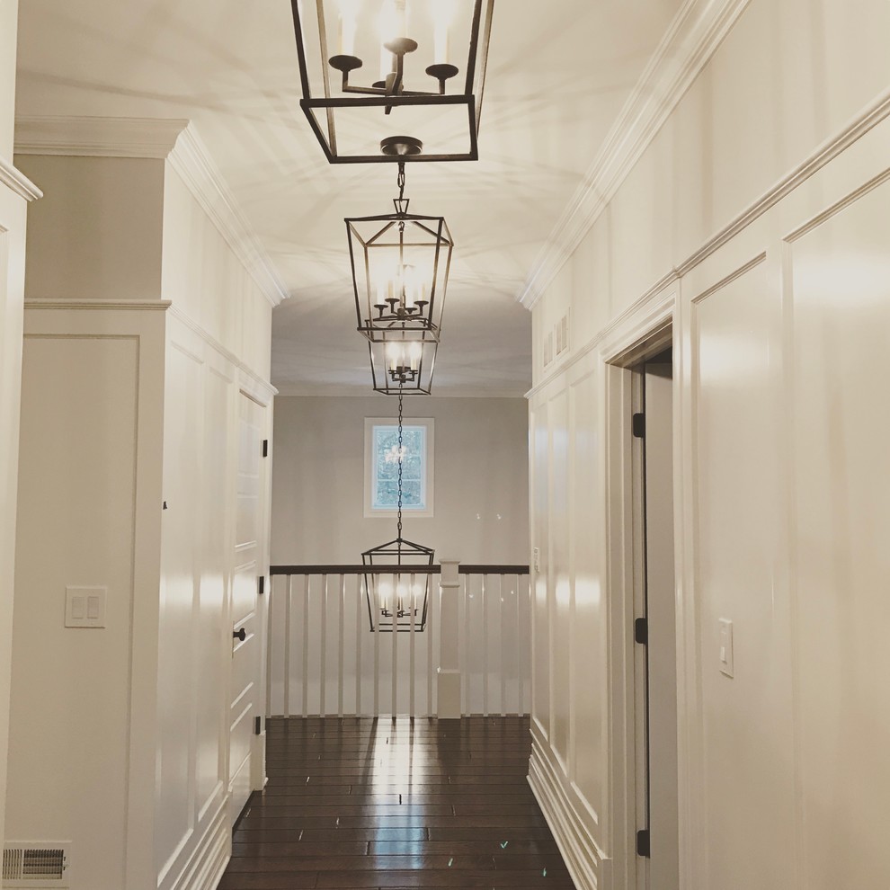 Photo of a mid-sized country hallway in Chicago with white walls and dark hardwood floors.