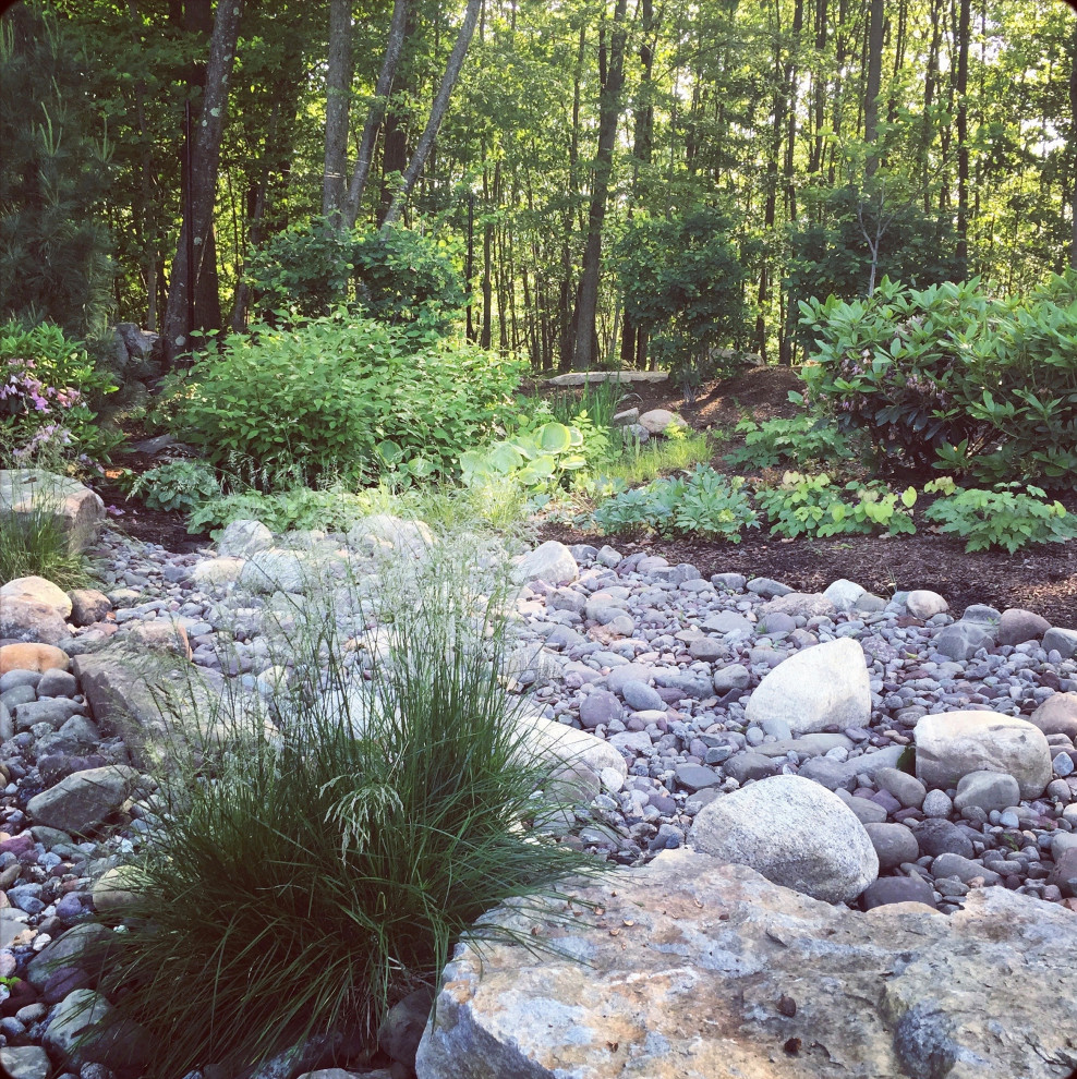 Photo of a mid-sized contemporary sloped partial sun xeriscape in New York with with flowerbed and natural stone pavers.