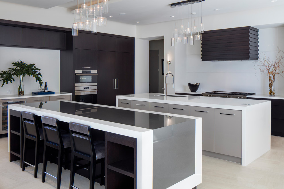 This is an example of a contemporary kitchen in Orlando with an undermount sink, flat-panel cabinets, dark wood cabinets, white splashback, glass sheet splashback, stainless steel appliances, multiple islands and beige floor.