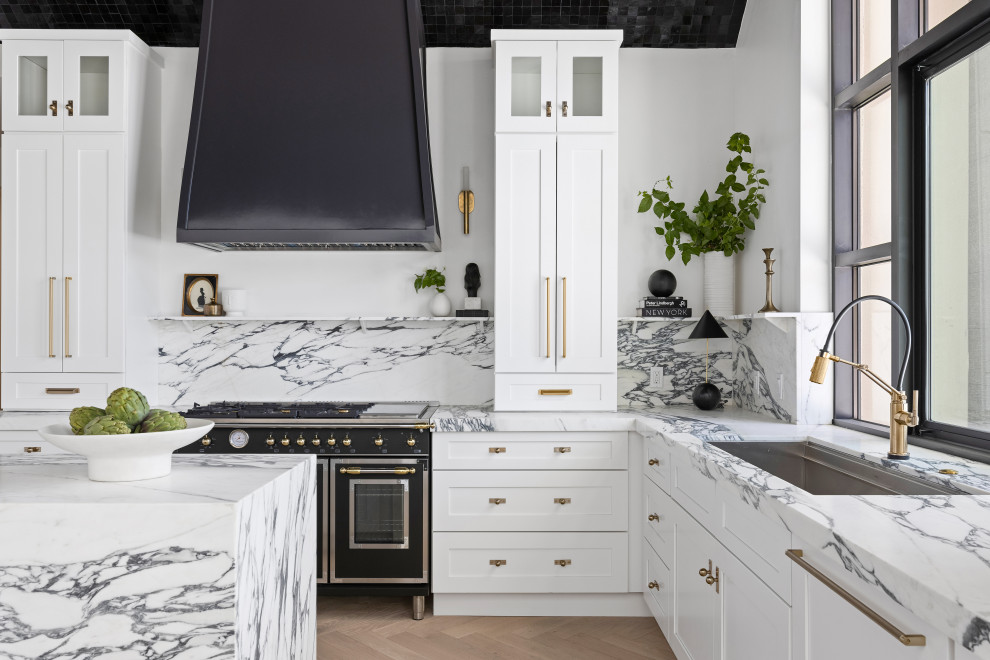 Inspiration för ett funkis vit vitt kök, med vita skåp, marmorbänkskiva, vitt stänkskydd, stänkskydd i marmor, svarta vitvaror, ljust trägolv, en köksö och brunt golv