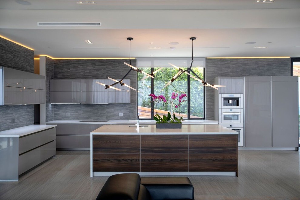 Inspiration for a large modern l-shaped open plan kitchen in Hawaii with flat-panel cabinets, grey cabinets, solid surface benchtops, grey splashback, panelled appliances, with island, white benchtop, an undermount sink, vinyl floors and grey floor.