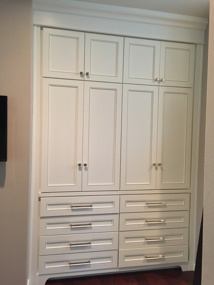 This is an example of a small traditional gender-neutral built-in wardrobe in Portland with recessed-panel cabinets, white cabinets and dark hardwood floors.