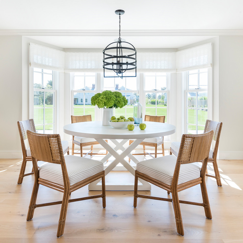 Photo of a beach style dining room in Providence with white walls, light hardwood floors and beige floor.