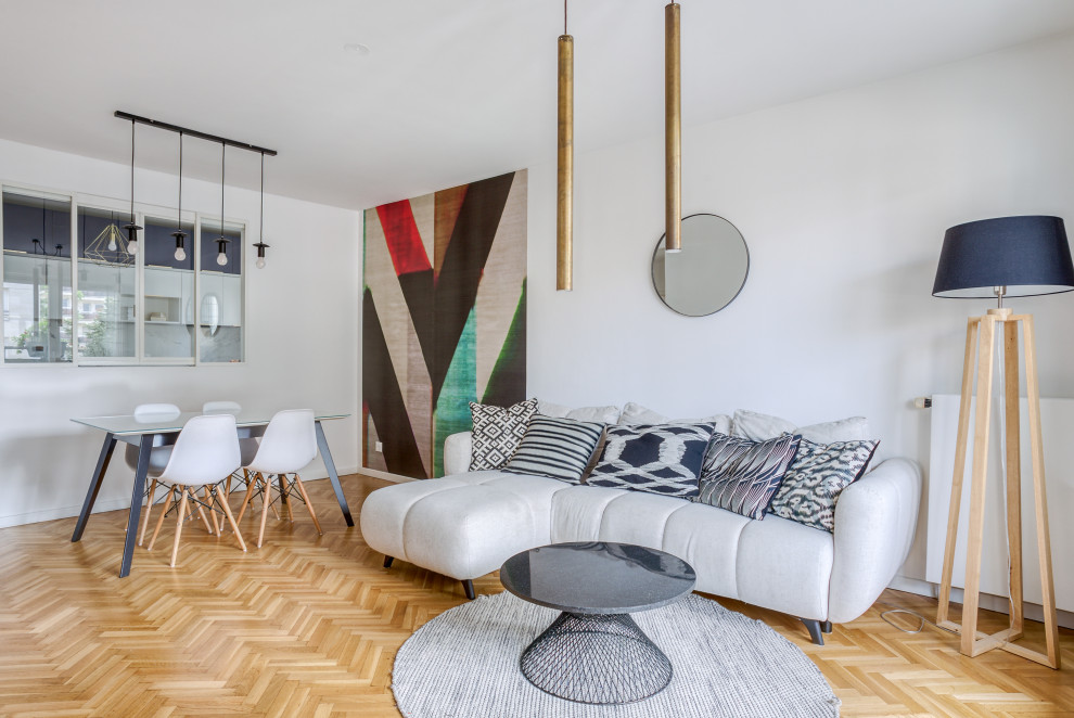 This is an example of a contemporary open concept living room in Paris with white walls, light hardwood floors and beige floor.