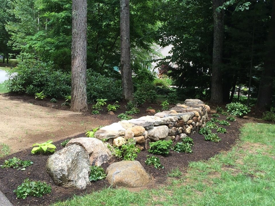 Mid-sized country front yard partial sun garden in Portland Maine with a retaining wall and natural stone pavers for summer.
