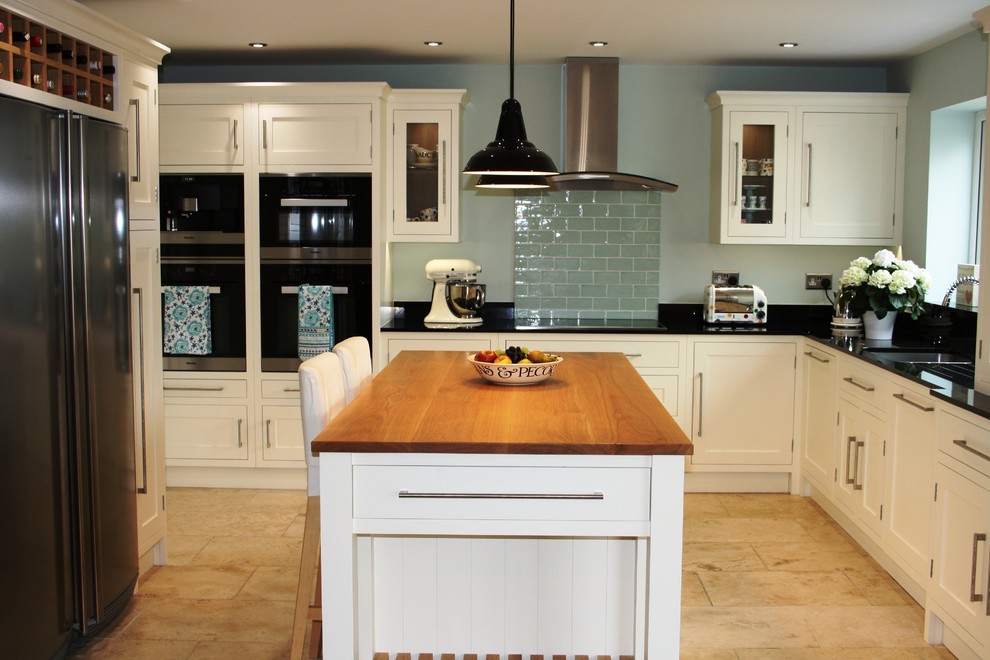 Inspiration for a mid-sized traditional u-shaped eat-in kitchen in West Midlands with an undermount sink, shaker cabinets, white cabinets, granite benchtops, green splashback, ceramic splashback, travertine floors, with island and black appliances.