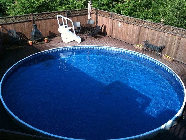 Backyard round aboveground pool in Other with decking.
