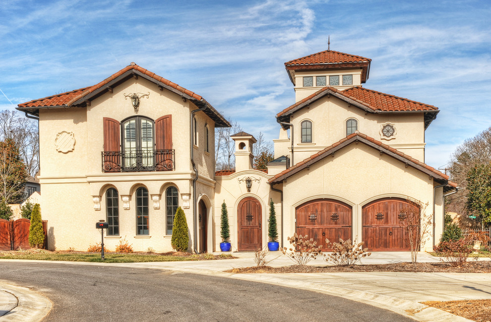 Photo of a large mediterranean three-storey stucco beige exterior in Charlotte with a gable roof.